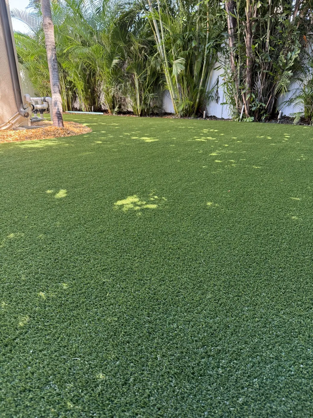 Close view of dense artificial turf blades in a shaded backyard