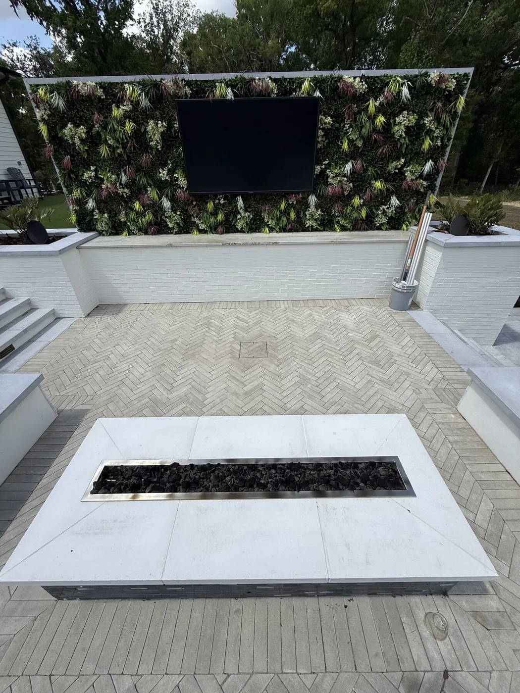 Herringbone paver patio with a fire table and a living wall behind it