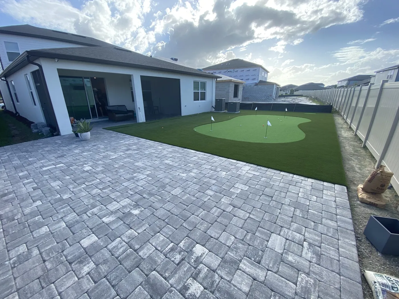 Putting green set in turf beyond a new paver patio