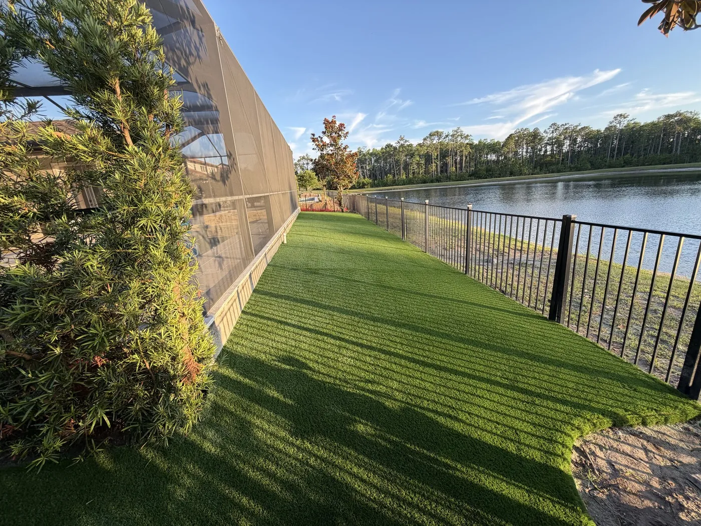 Turf side yard along a screened pool enclosure with a lake view