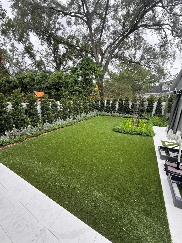 Freshly installed artificial lawn running along a home with a clean stone border