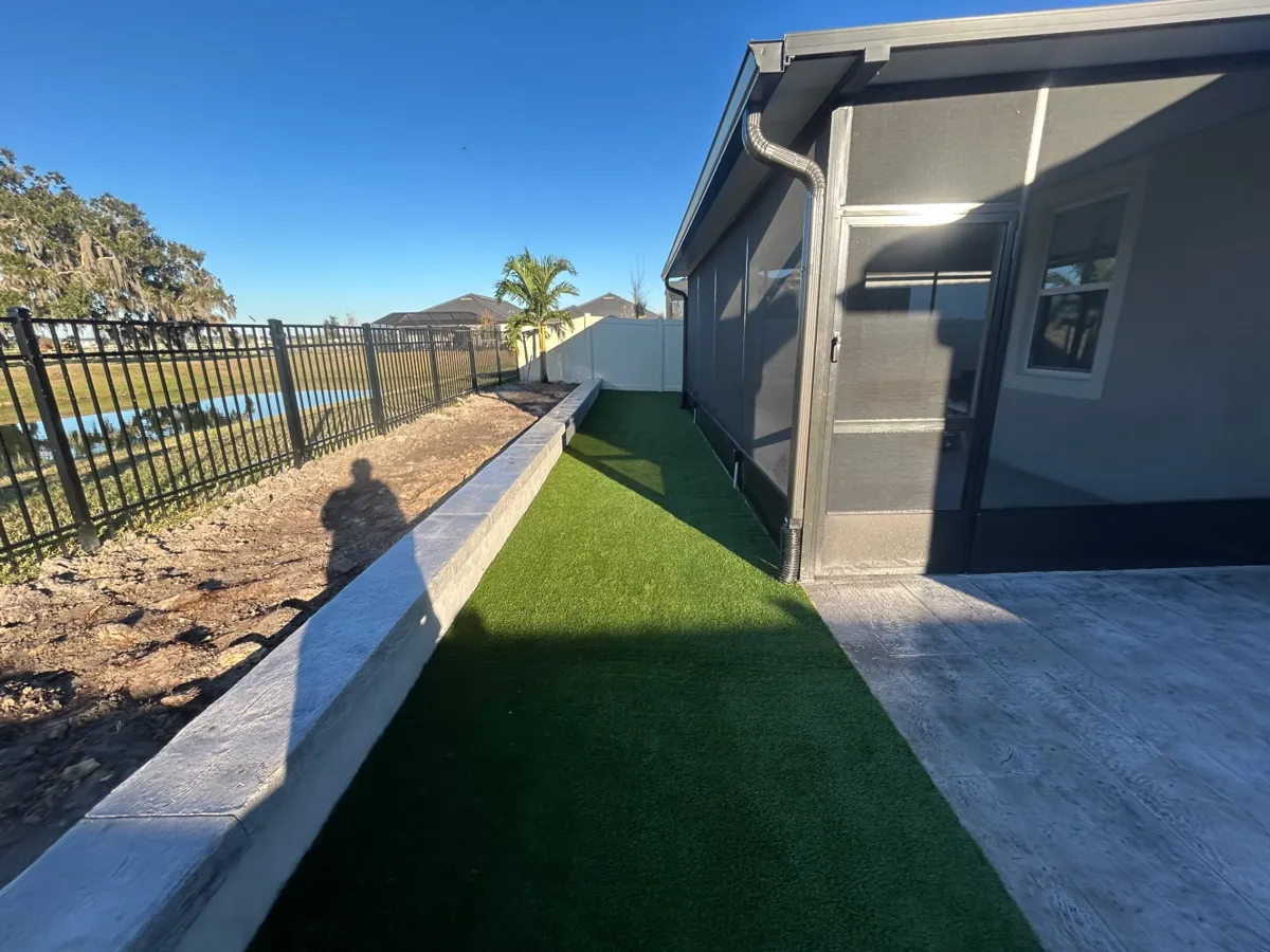 Turf side yard along a home with a fenced lake view