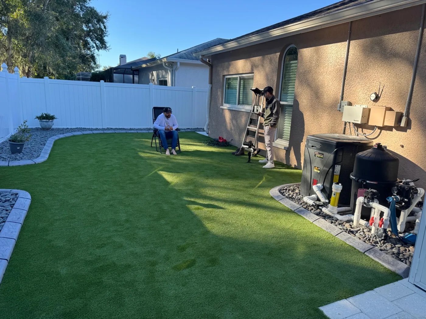 Our crew installing artificial turf in a fenced backyard