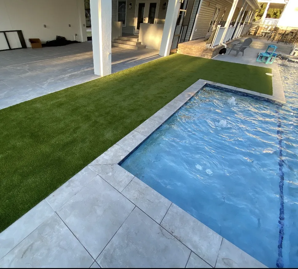 Turf bordering a pool with light paver coping