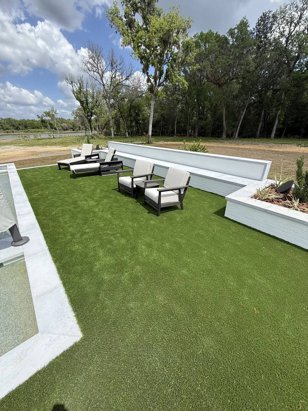 Turf lawn beside the pool with lounge chairs