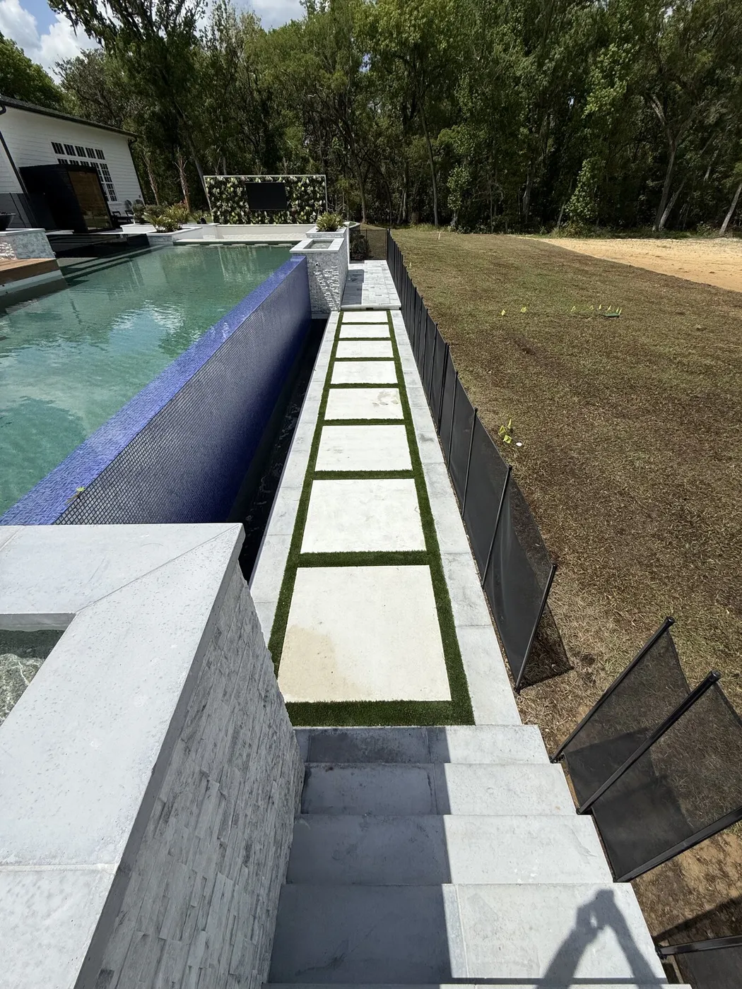 Stone steppers set into turf along the pool