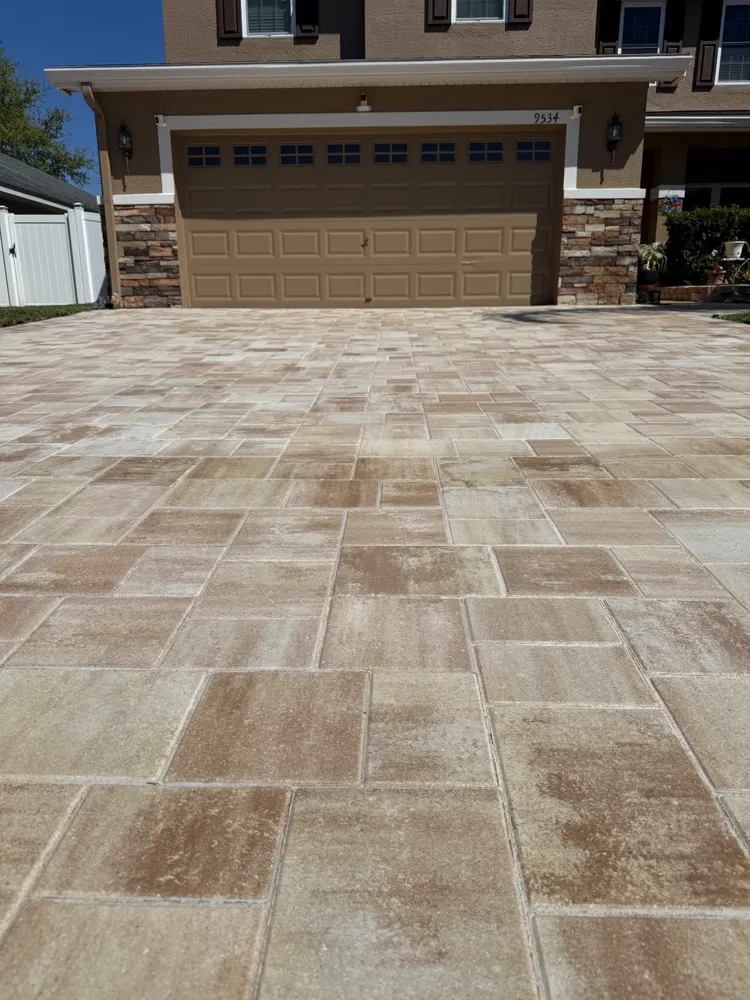 Travertine-look paver driveway leading up to a two-car garage